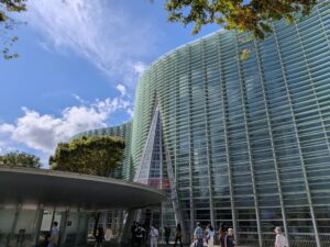 青空の下に広がる国立新美術館のガラス張りの外観
